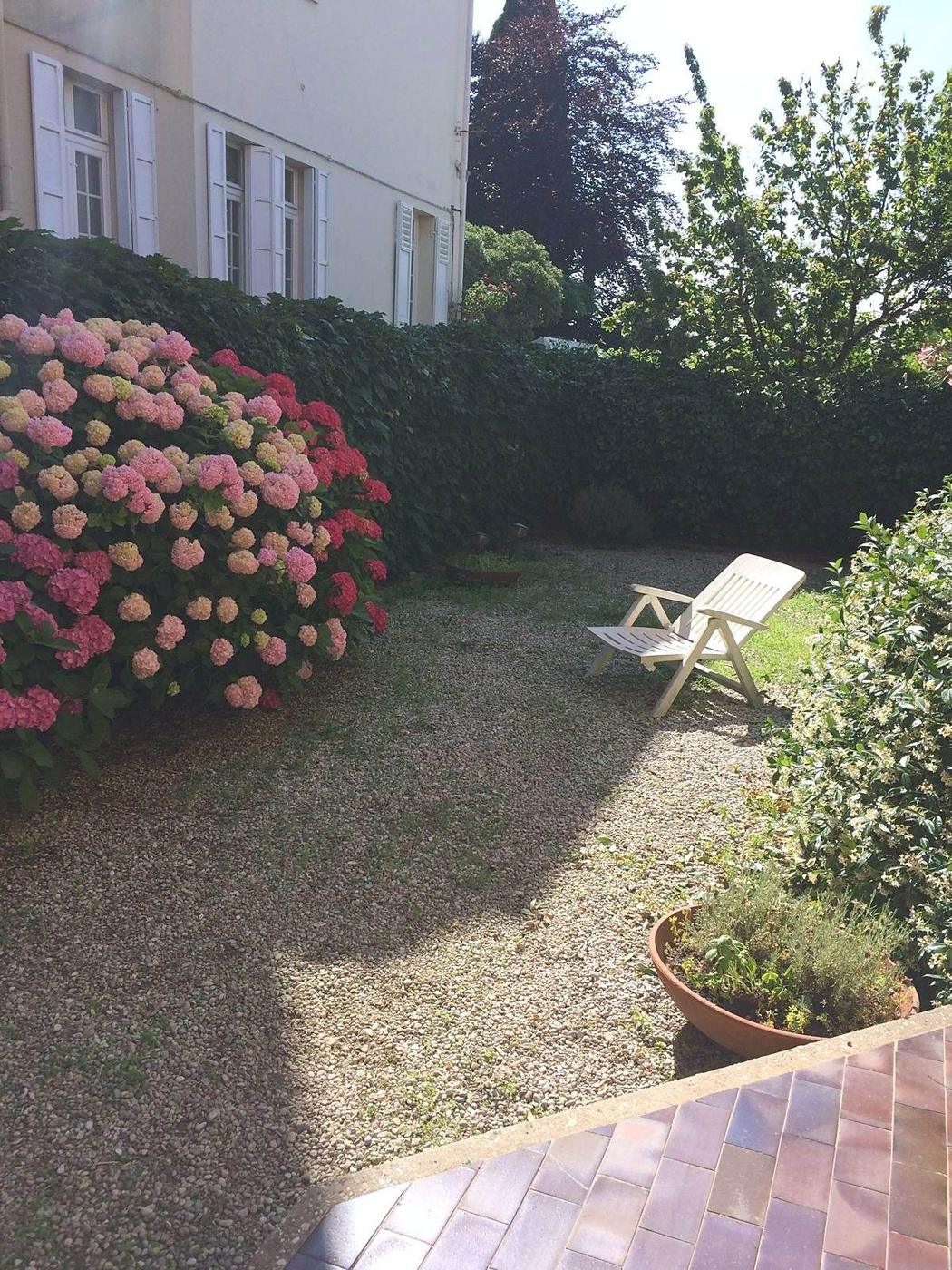 Angolo ombreggiato del giardino con sdraio e ortensie